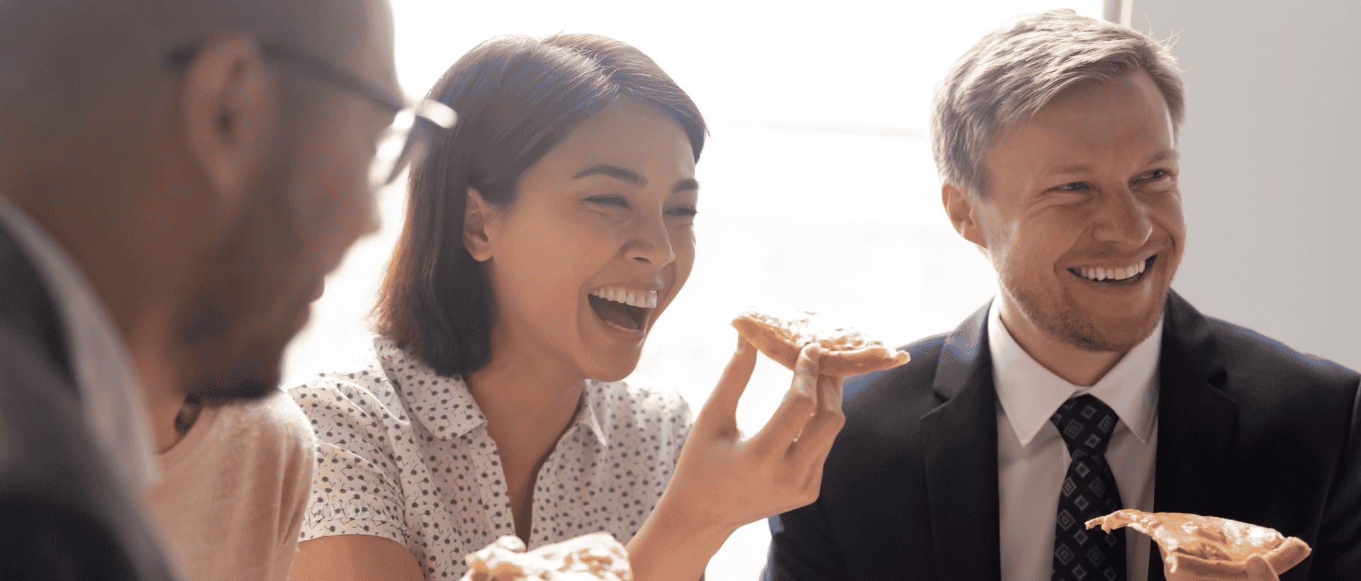 A group of coworkers eating Bertucci's pizza at a corporate event.