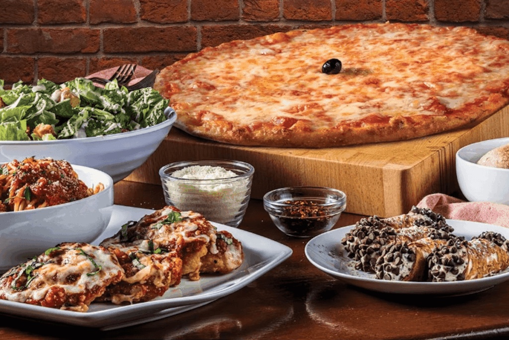 Bertucci's catering featuring a cheese pizza, chicken parmesan, spaghetti and meat sauce, caesar salad, cannoli, side of rolls, crushed red pepper, and parmesan cheese