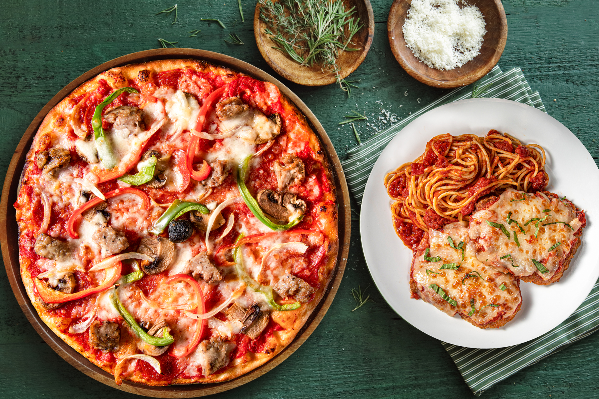A pizza and chicken parm on a green tablecloth