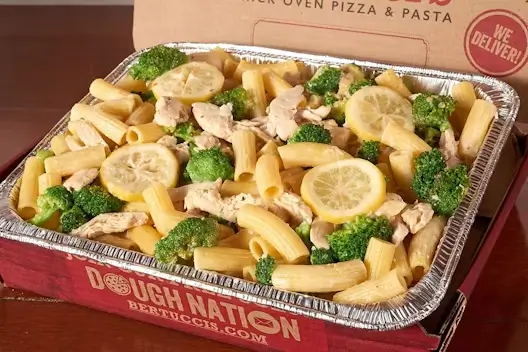 A catering tray of fresh broccoli, rigatoni, roasted chicken & lemon-garlic cream sauce