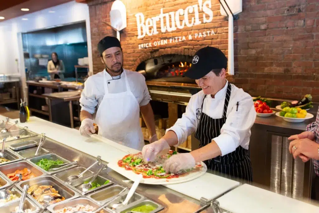 Two of Bertucci's Chefs making pizza behind the counter
