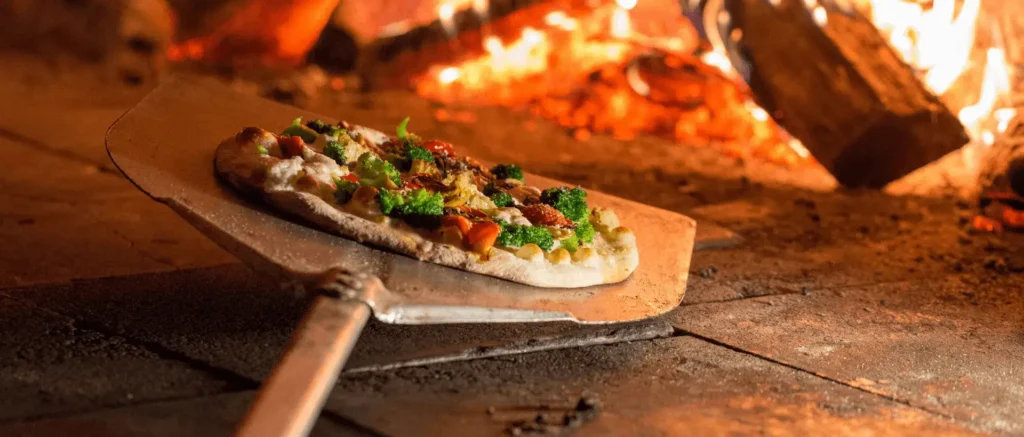 A pizza baking in a brick pizza oven